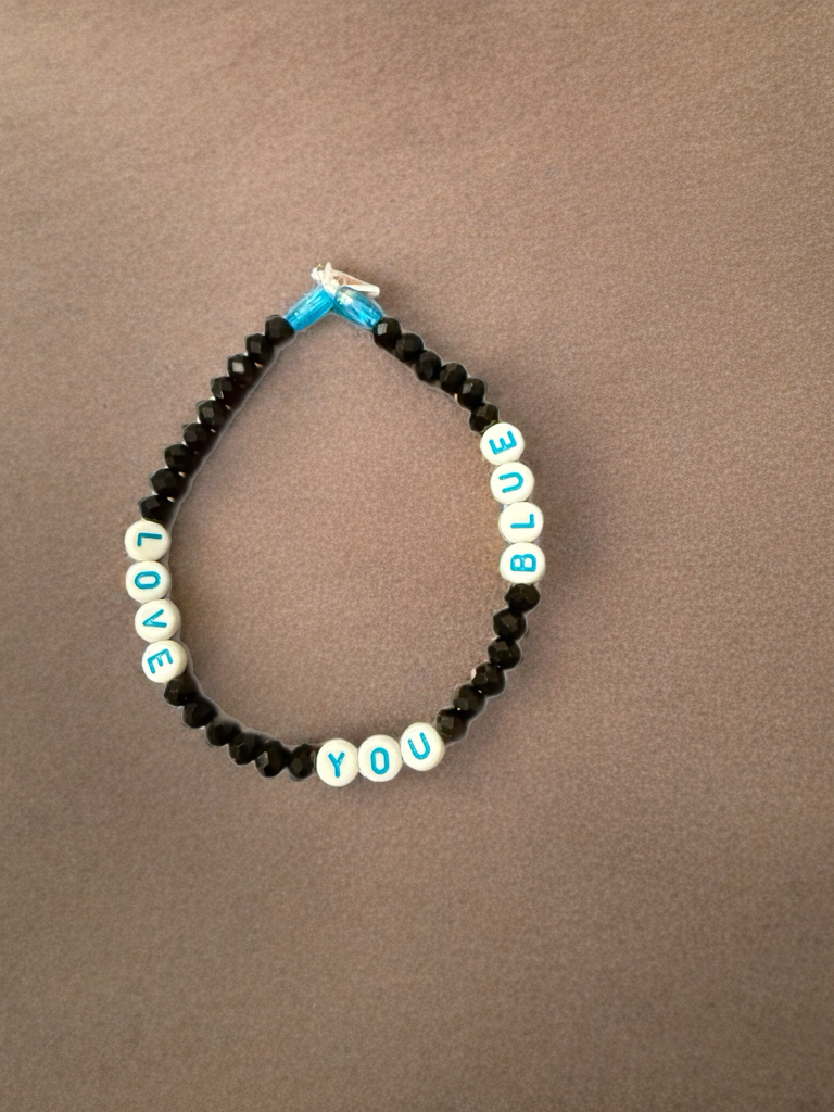 Black beaded bracelet with white and blue “LOVE YOU BLUE” letter beads and blue ribbon.