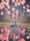 Decorative stand with red, white, and blue beaded hoop earrings against a blurred bokeh background.