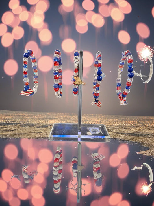 Decorative stand with red, white, and blue beaded hoop earrings against a blurred bokeh background.