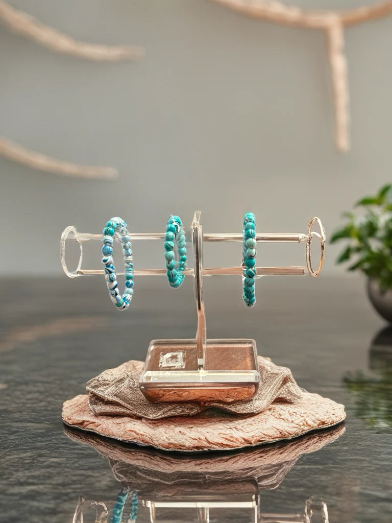 Turquoise beaded bracelets on a gold stand with a neutral background