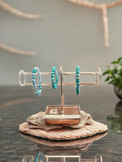 Turquoise beaded bracelets on a gold stand with a neutral background